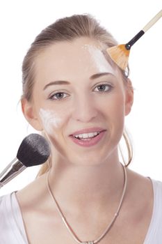 young beautiful woman applying mineral powder on face isolated