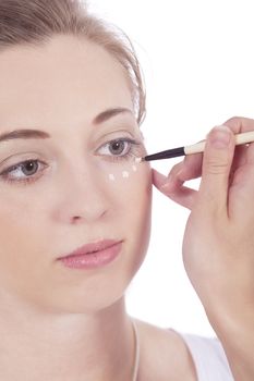 young beautiful woman applying concealer on face isolated