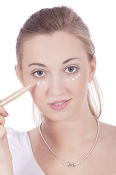young beautiful woman applying concealer on face isolated
