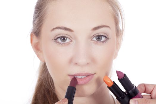 young beautiful woman applying colored lipstick on lips isolated