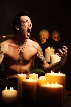 Photo of a male vampire resting in a leather chair and fangs showing.  Harsh and dark lighting for scarier feel.