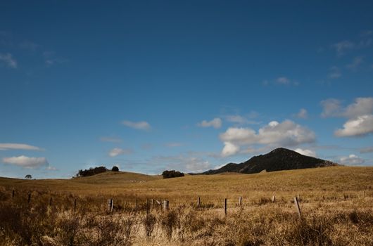 Australian dry winter pasture treeless landscape with clouds buiding in blue sky