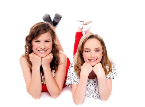 Girls posing with hands on chin. Lying on floor isolated over white background