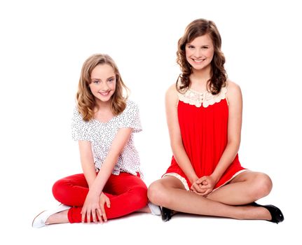 Two glamorous friends sitting together smiling at camera