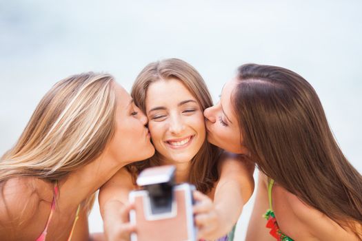 three teenager beautiful girls taking selfie with old camera on the beach