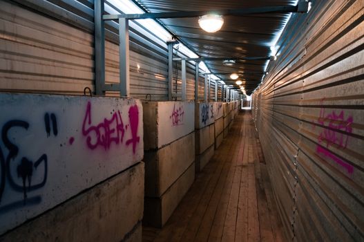 Tunnel with concrete blocks and metal walls with graffiti