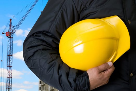 Closeup  of Yellow helmet at builder hands on building background