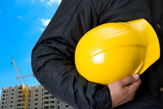 Closeup  of Yellow helmet at builder hands on building background