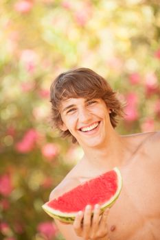 Portrait of a beautiful young man eating watermelon