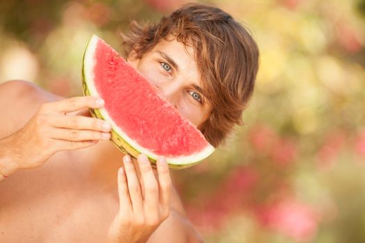 Portrait of a beautiful young man eating watermelon