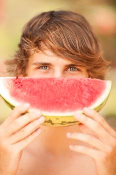 Portrait of a beautiful young man eating watermelon