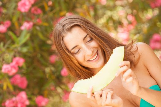 Portrait of a beautiful young woman eating melon