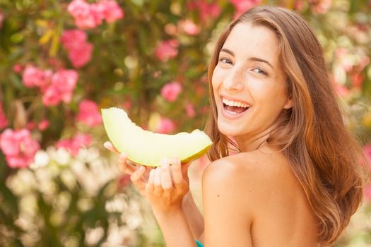 Portrait of a beautiful young woman eating melon