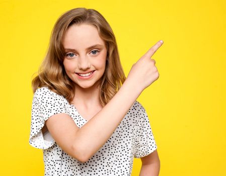 Smiling caucasian girl indicating upwards. Isolated against white background