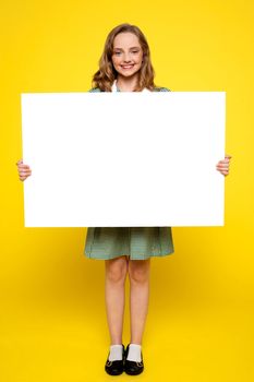 Teenager showing white blank billboard isolated against yellow background
