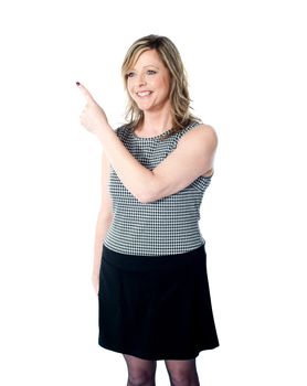 Smiling woman pointing towards copy space area and looking away. All on white background