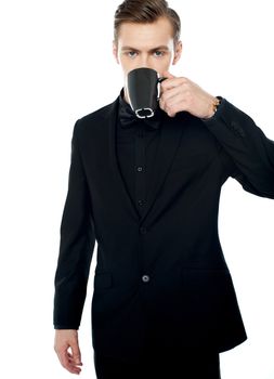 Smart young man drinking coffee in black cup over white background