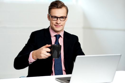 Male executive holding cup of coffee against gray background. Refreshment break