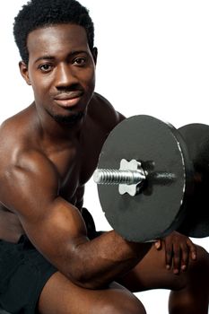 Powerful young man lifting weights. Looking at camera while exercising