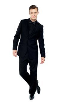 Isolated young man standing with crossed legs dressed in party wear