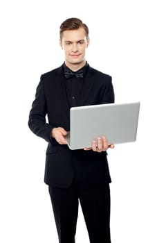 Casual young man holding laptop in hands and smiling at camera