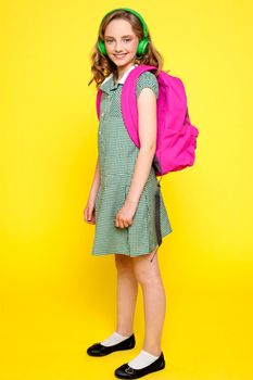 Portrait of a school girl wearing headphones and carrying school bag