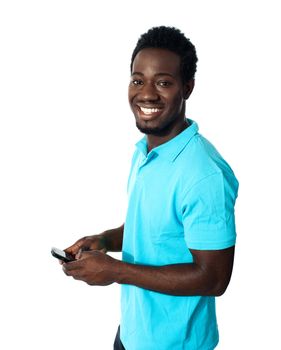 Handsome african man using cellphone, smiling and looking at camera