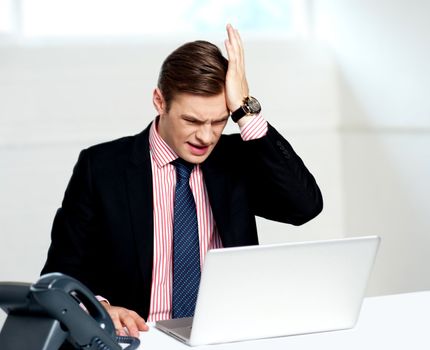 Unhappy businessperson looking at his laptop. Business loss