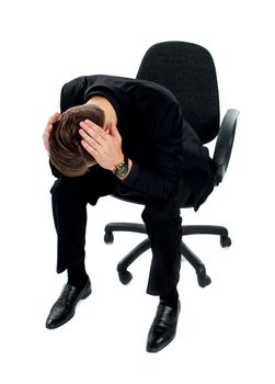 Frustrated man sitting on chair with hands on his head
