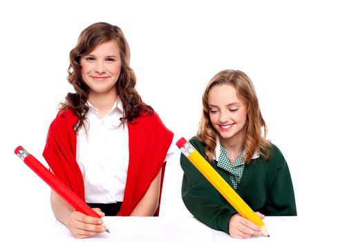 Cheerful girls writing with pencil on surface isolated against white background