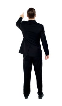 Rear view of a male model pointing at copy space over white background