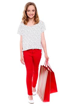 Little girl walking with shopping bag against white background