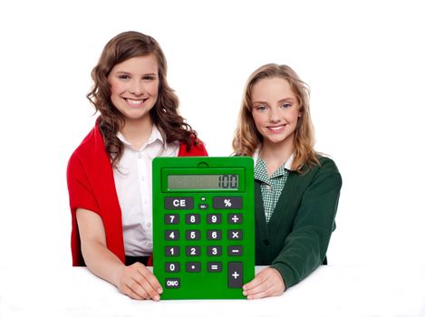 Girls showing big green calculator to camera against white background