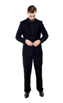 Full length portrait of handsome young gentleman tucking his coat button