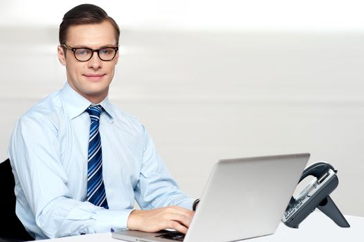 Handsome corporate male tying on laptop. working in office