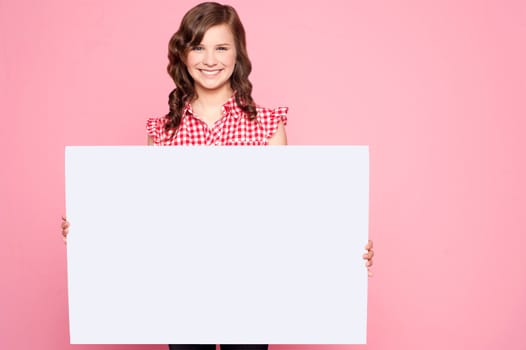 Beautiful girl holding blank billboard and looking at camera