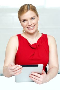 Beautiful young woman holding portable tablet pc isolated against gray background