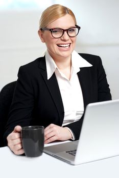 Attractive female smiling with black coffee cup in hand. At work desk