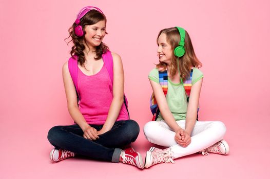 Seated beautiful teenagers looking at each other. Pretty schoolgirls