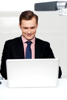 Smiling business male watching videos on laptop in office