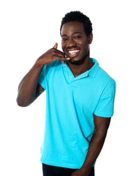 Smiling young man showing calling gesture isolated on white background