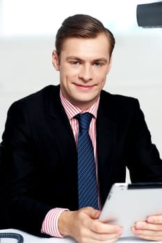 Young executive posing with tablet pc and smiling at camera
