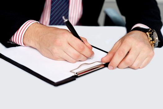 Closeup shot of male's hand writing on blank notepad