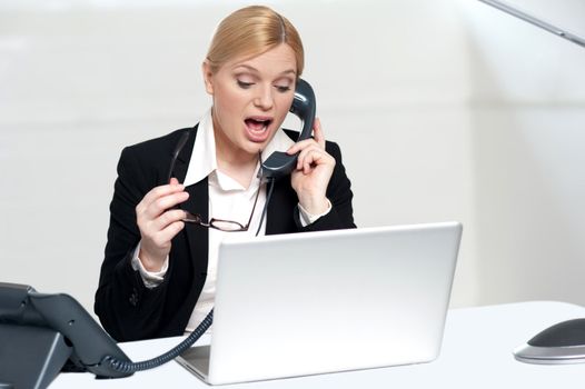 Woman trying to convince client over the phone. Holding glasses in hand