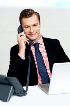 Handsome corporate man communicating on phone and smiling at camera