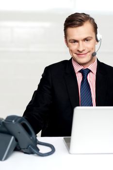 Male executive wearing headsets and smiling. Sitting in office