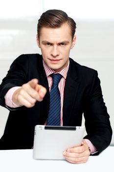 Tech savvy corporate man pointing at you. Serious look on face