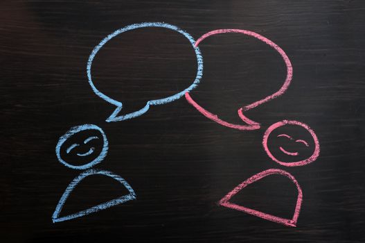 Chalk drawing of blank speech bubbles with human figures on a blackboard background