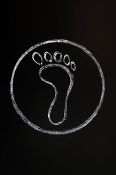 Chalk drawing of footprint symbol on a blackboard background with a circle