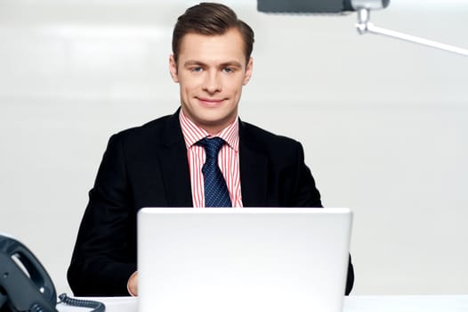 Portrait of handsome young businessman with laptop in office